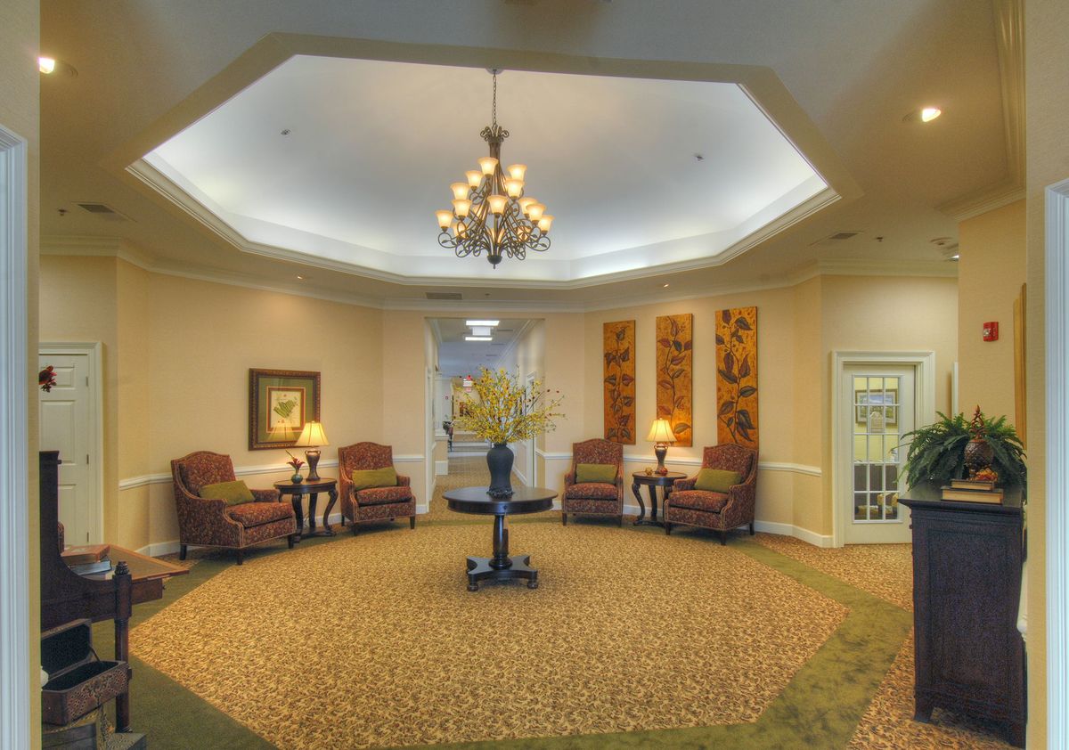A spacious lobby area featuring a central chandelier, comfortable seating, and decorative elements.