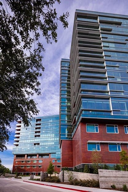 A view of modern glass-facade buildings against a cloudy sky.