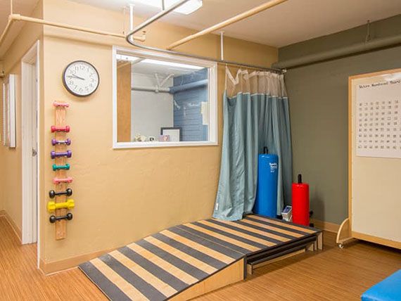 A physical therapy room equipped with a ramp, exercise balls, and other rehabilitation tools.