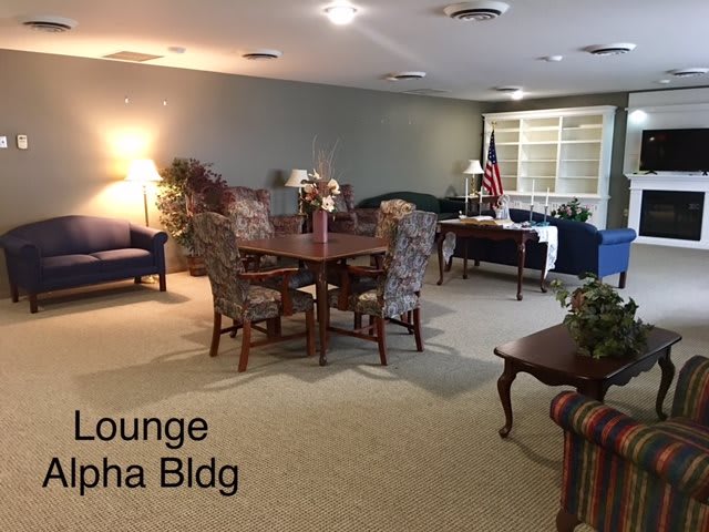 A cozy lounge area with a table, chairs, sofas, and carpeted flooring.