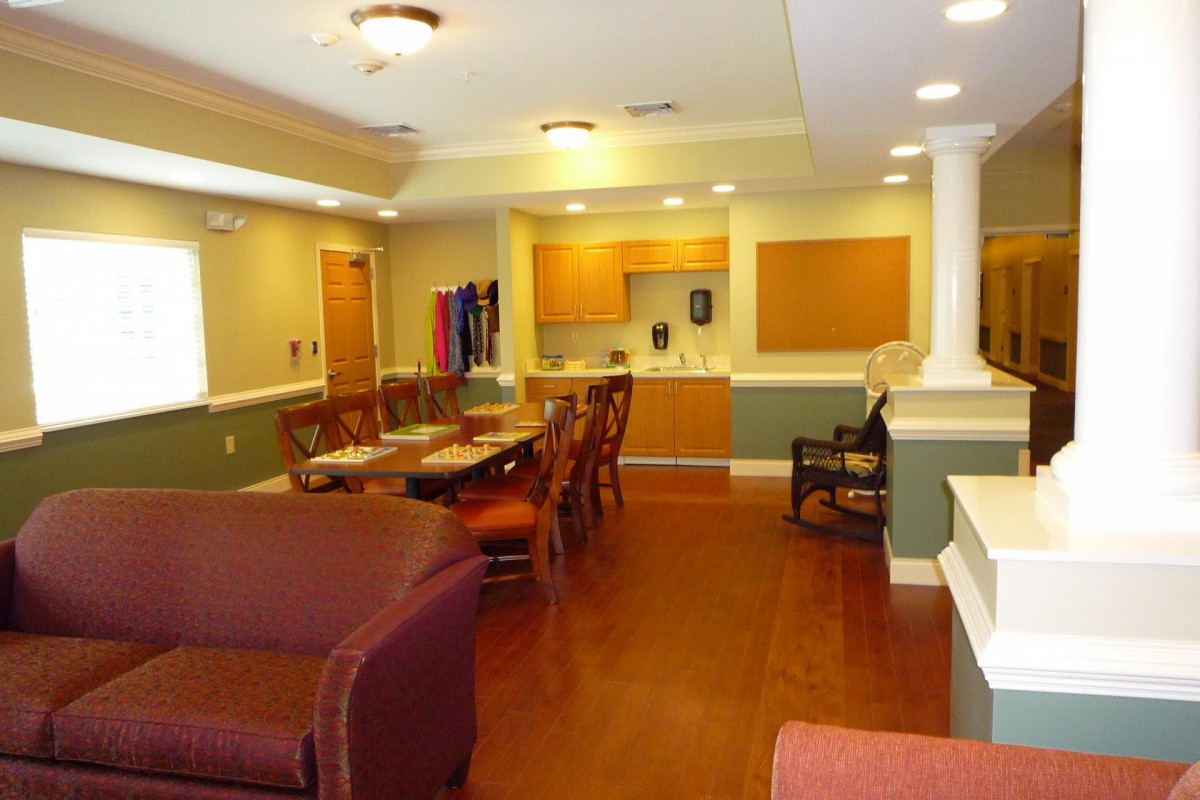 A communal living area featuring a dining table, kitchen, and lounge seating.