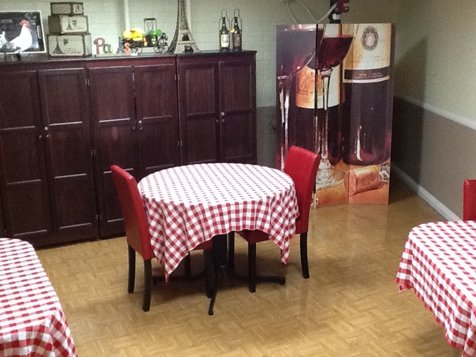 A cozy restaurant interior with tables covered in red and white checkered tablecloths.