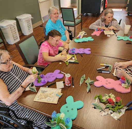 A group of elderly individuals engaged in a fun crafting activity, creating colorful decorations with flowers.