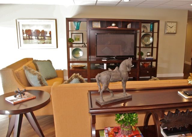 A cozy living room featuring a television, sofa, and decorative horse sculpture.