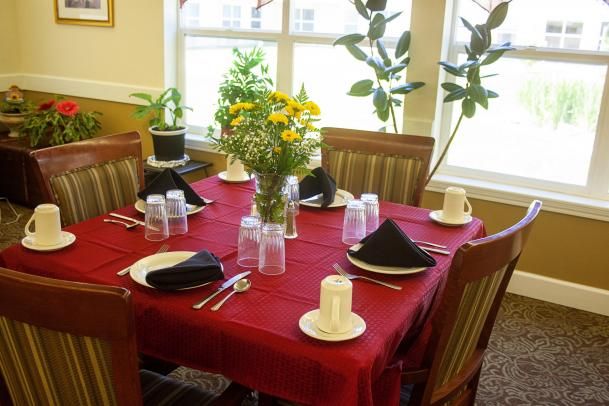 A dining table set with a red tablecloth, black napkins, and a floral centerpiece.