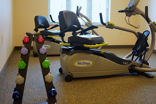 A well-equipped fitness area featuring a recumbent bike and weight rack.