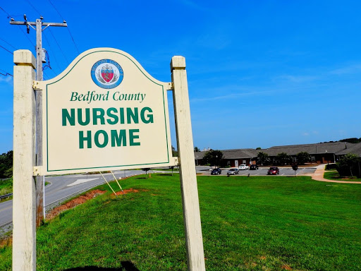 A sign for the Bedford County Nursing Home, surrounded by a grassy area and clear blue skies.
