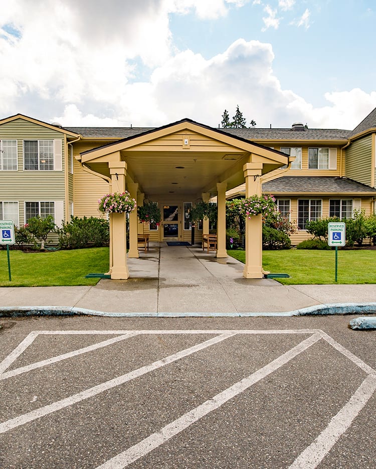 Entrance of a building with covered walkway and landscaped surroundings.