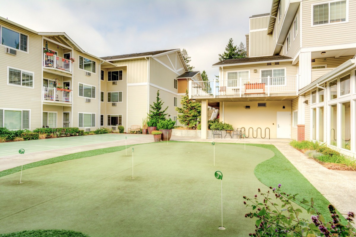 An apartment complex featuring a well-maintained outdoor putting green surrounded by modern residential buildings.