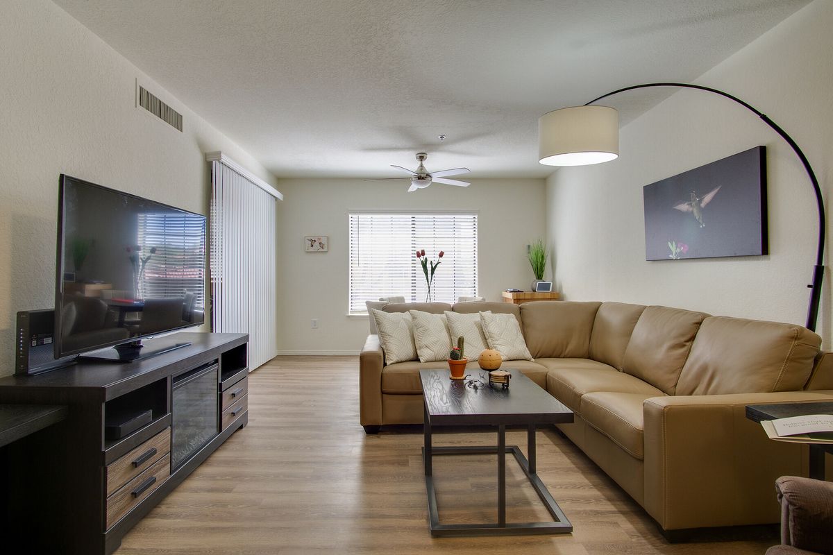 A modern living room with a large sofa, flat-screen TV, and stylish decor.