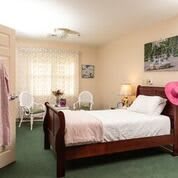 A cozy bedroom with a wooden bed, soft lighting, and pastel decor.