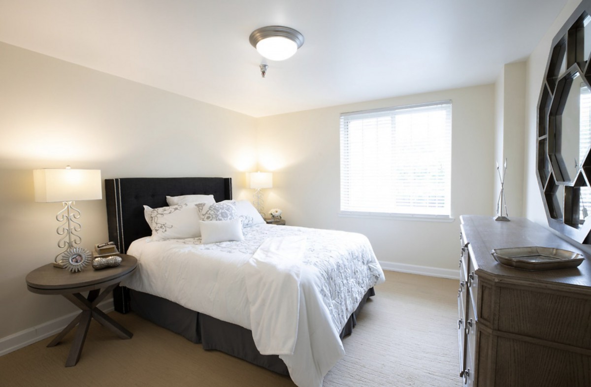 A bright and minimalist bedroom with a neatly made bed and ample natural light.