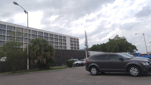 A view of a hotel building with vehicles parked in the foreground under a cloudy sky.