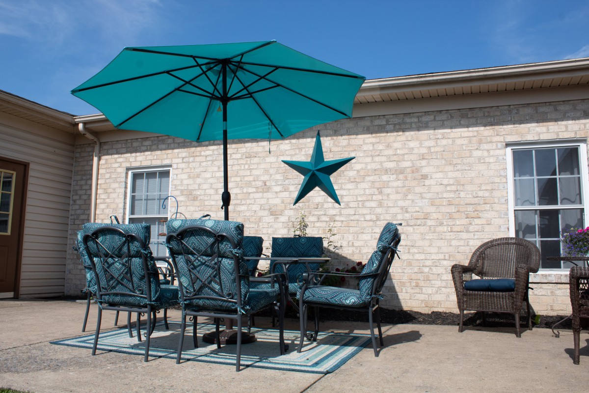 A cozy patio setup featuring teal outdoor furniture and a large umbrella.