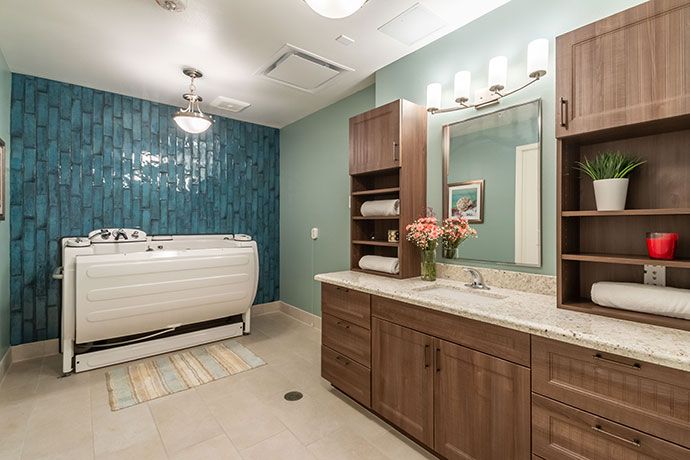 A modern bathroom with a sleek bathtub and wooden vanity, featuring a large mirror and decorative elements.