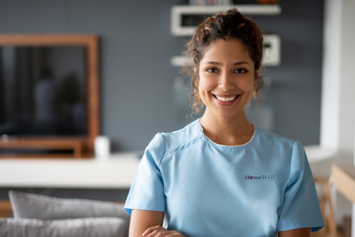 A woman in scrubs smiling indoors.