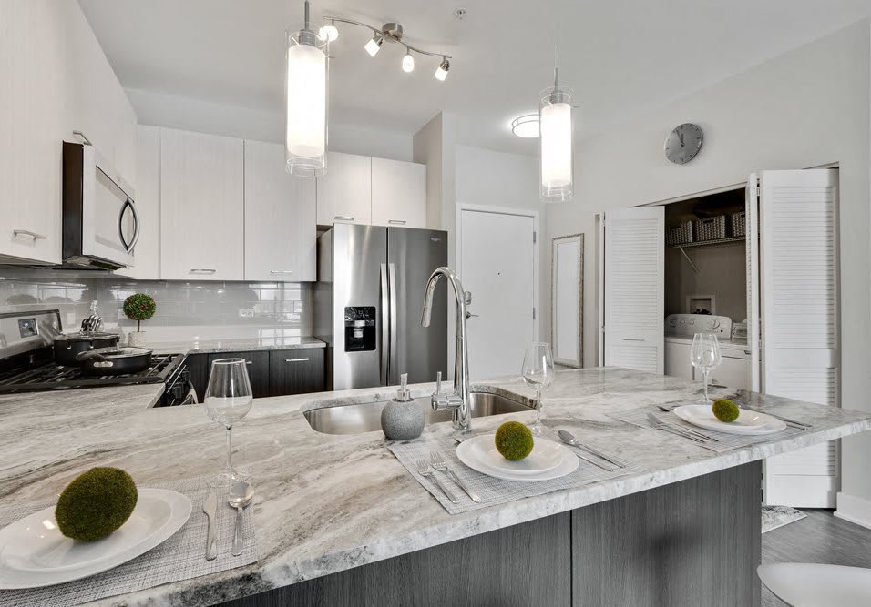 A modern kitchen with stainless steel appliances and a marble countertop.