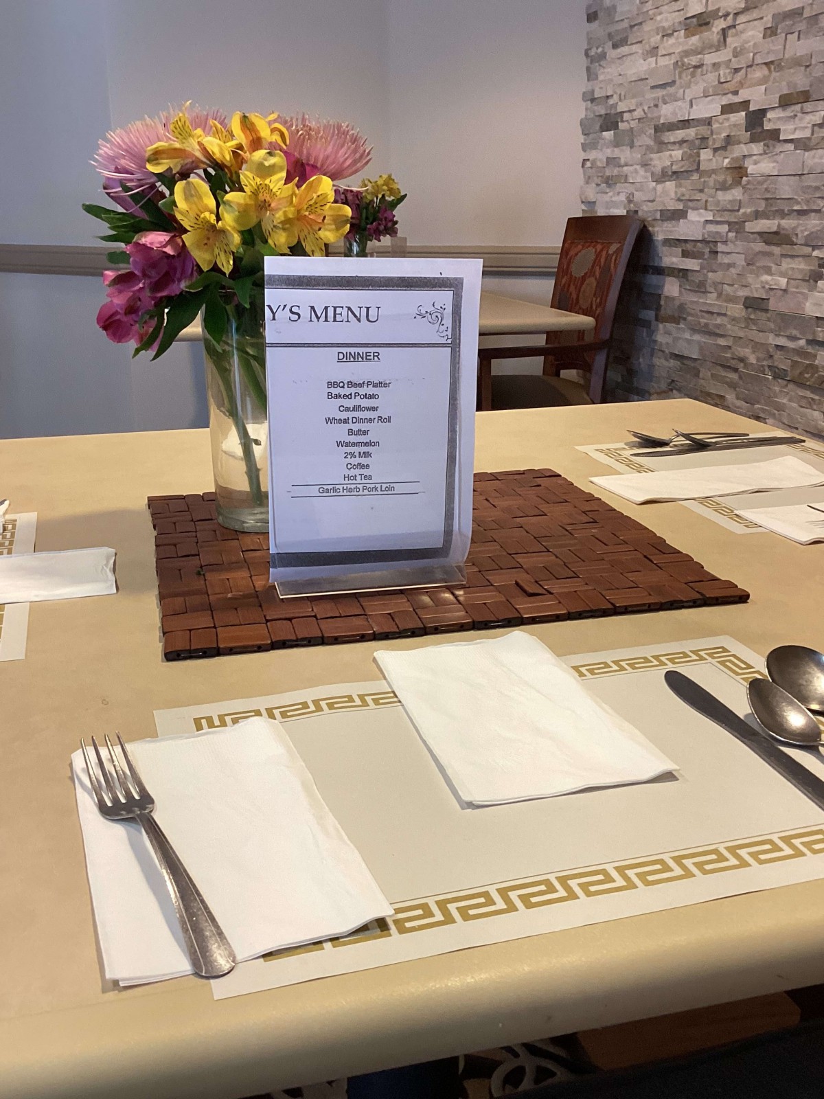 A restaurant table set with a menu and a vase of flowers.
