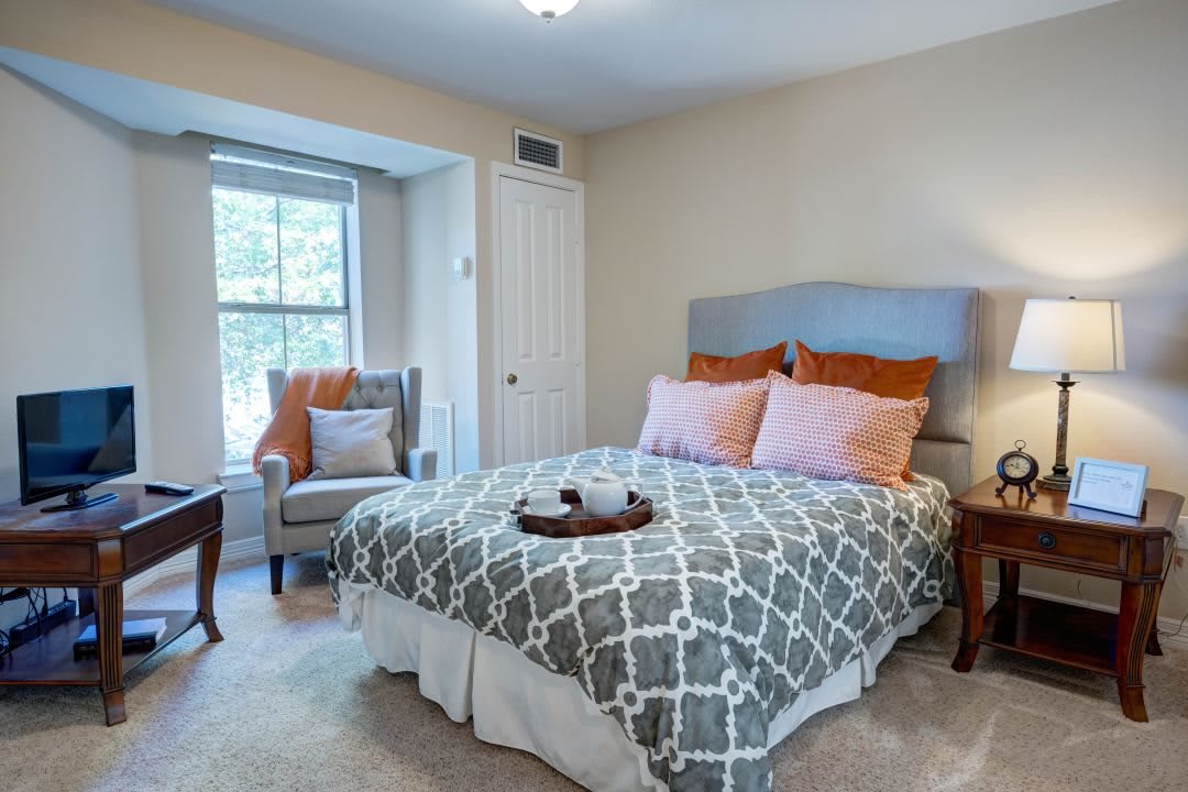 A cozy bedroom with a stylish bed, accent chair, and soft natural lighting.