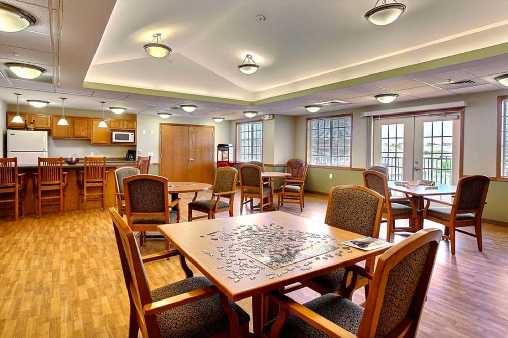 A cozy room with several tables and chairs, featuring a puzzle in progress.