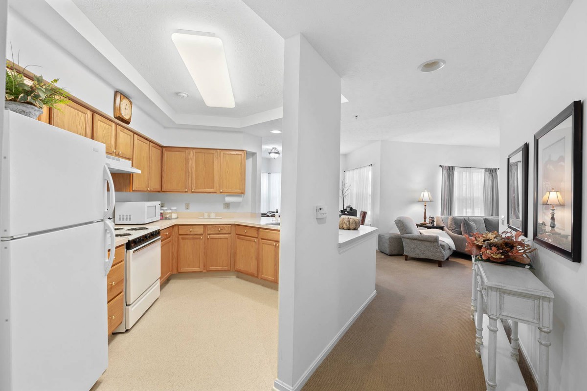 A cozy apartment interior featuring a kitchen with wooden cabinets and an adjacent living room area.