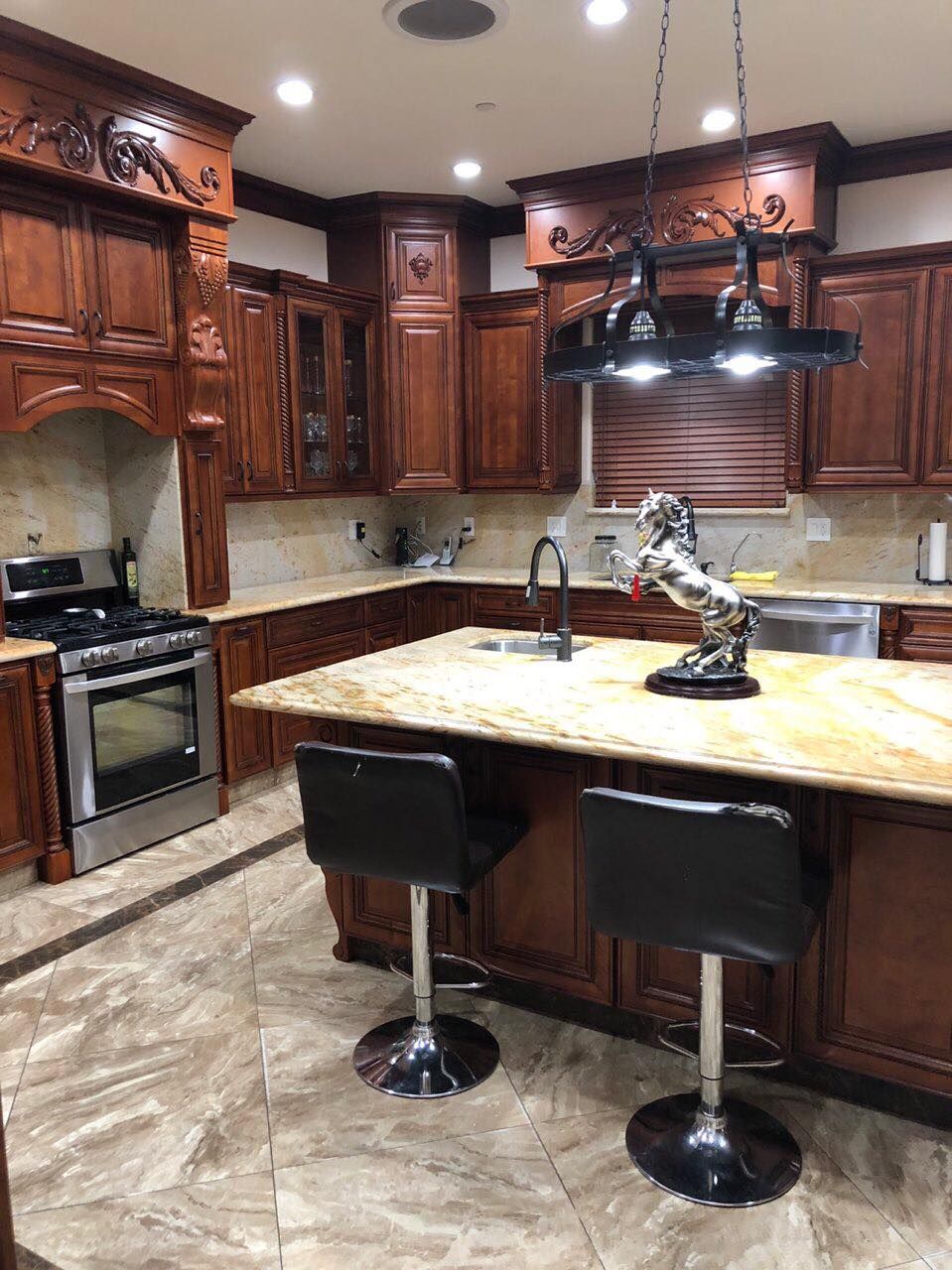 A modern kitchen featuring wooden cabinets, a central island with stools, and sleek lighting.