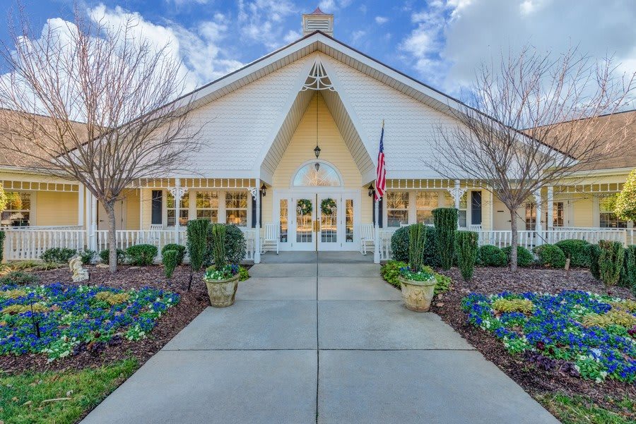 A picturesque church with a manicured garden and pathway under a blue sky.