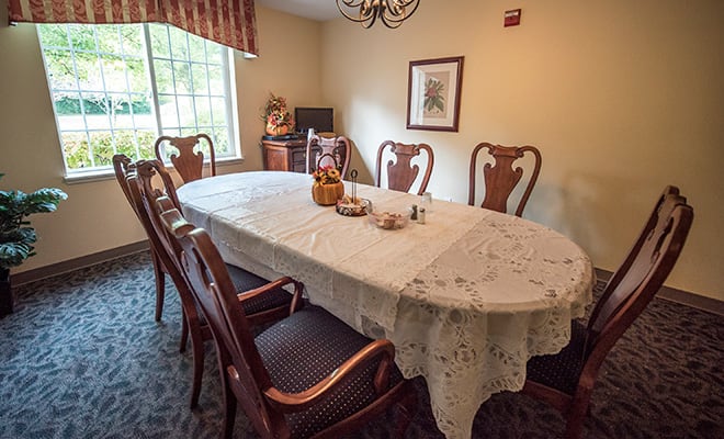 A cozy dining room with a lace-covered table and elegant wooden chairs.