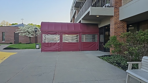 A maroon tent set up at the entrance of a building, providing shelter.