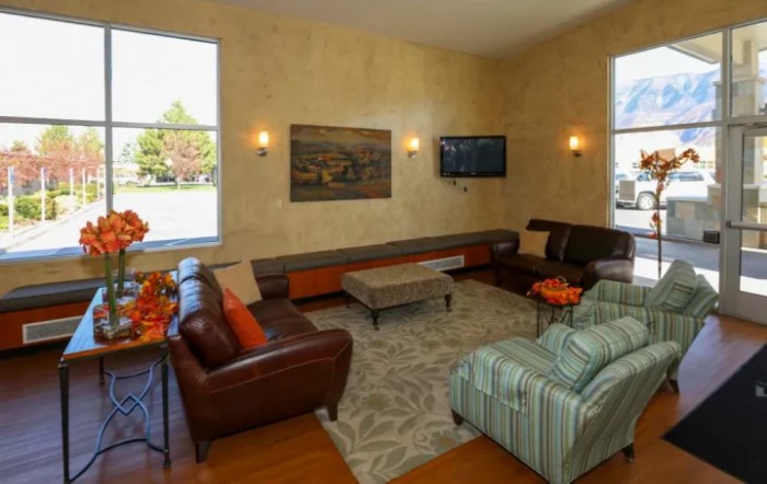 A cozy living room with sofas, armchairs, and a coffee table, adorned with wall art and a television.