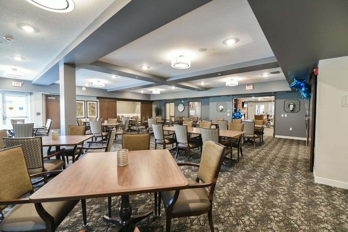 A spacious dining room with neatly arranged tables and chairs, featuring modern interior design and ceiling lighting.