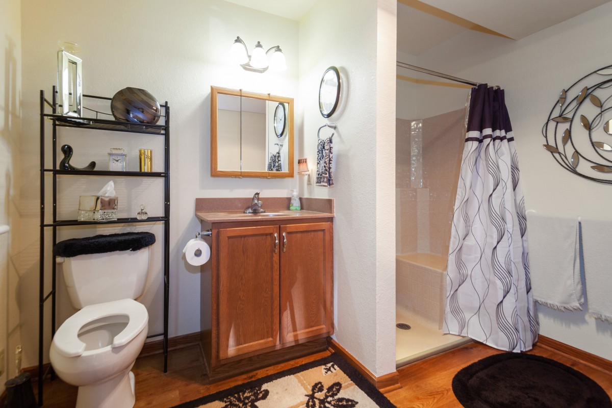 A well-organized bathroom featuring a sink with a mirror above, a toilet, and a shower area with a curtain.