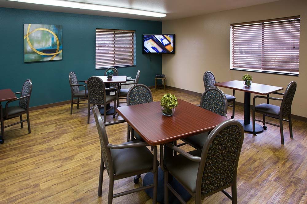 A small dining room with several tables and chairs, a television on the wall, and decorative elements.
