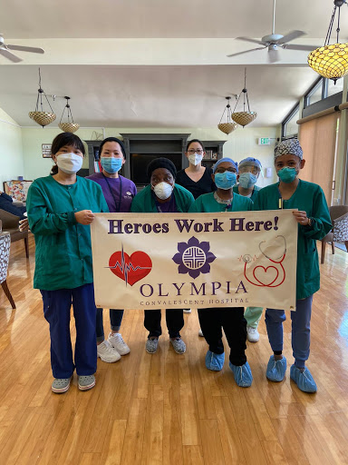 Healthcare workers proudly display a banner recognizing their dedication and hard work.