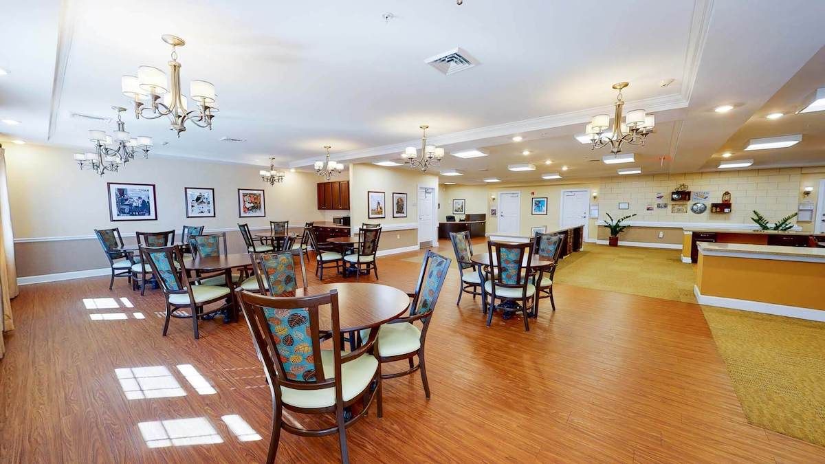 A spacious and elegantly decorated dining room with multiple tables and chairs arranged on a hardwood floor.