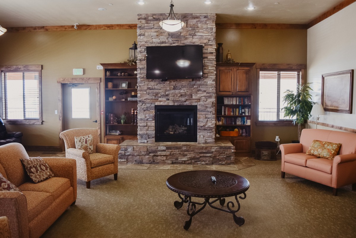 A cozy living room with a stone fireplace, flanked by bookshelves and centered around a round coffee table with comfortable seating.