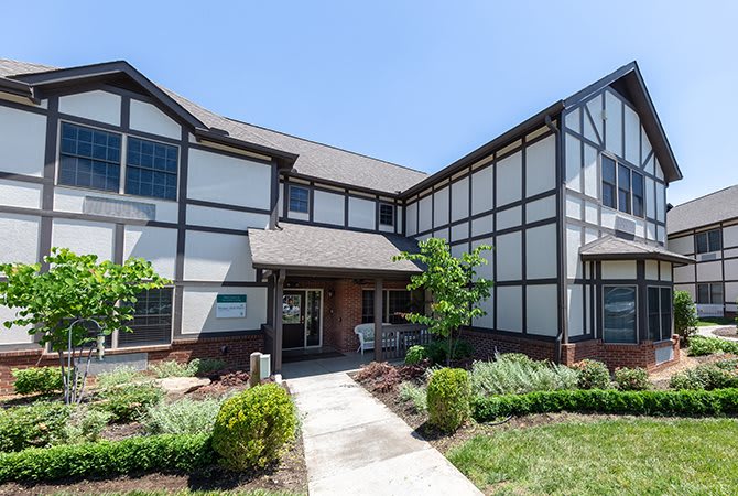 A Tudor-style residential building with manicured landscaping on a sunny day.