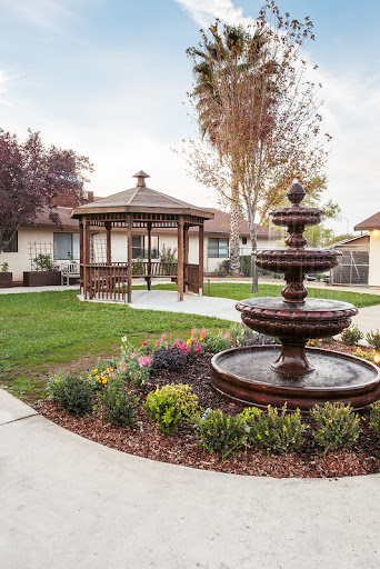 A serene garden featuring a charming gazebo and a decorative fountain, surrounded by vibrant flowers and manicured lawns.