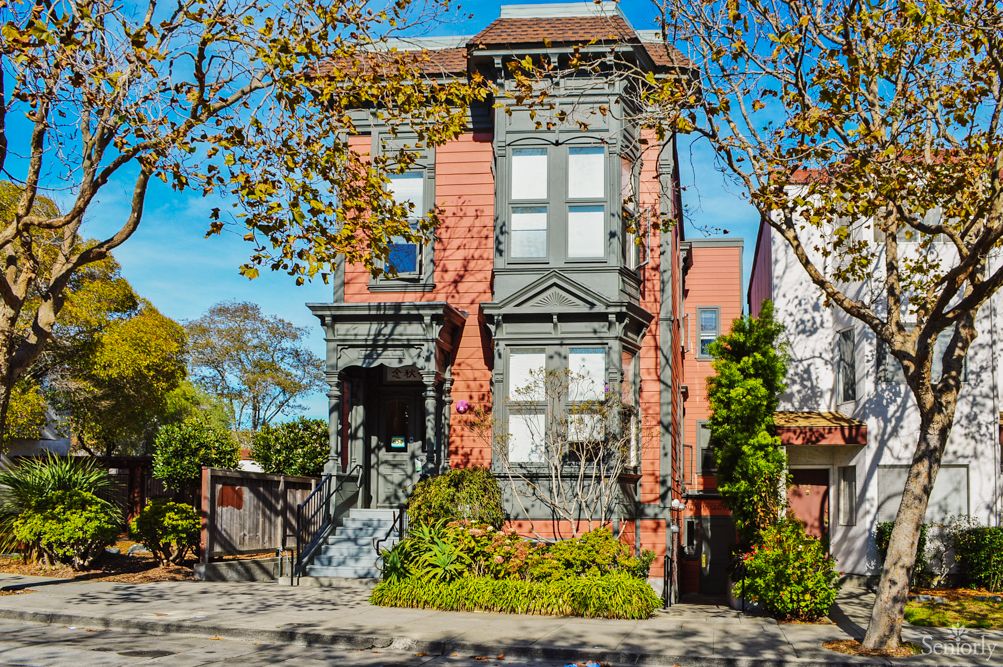 A historic Victorian house surrounded by autumn trees.