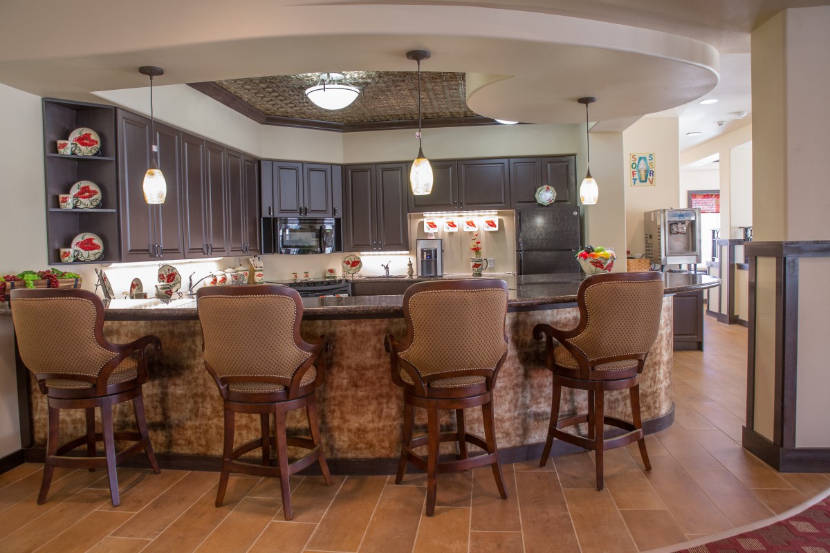 A modern kitchen featuring a large countertop with bar stools and pendant lights.