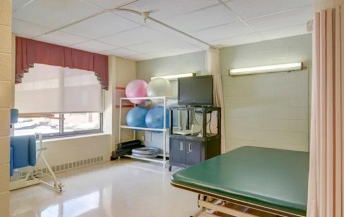 A rehabilitation room with exercise equipment and a treatment table.