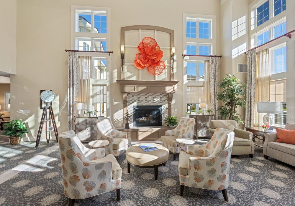 A modern living room with stylish furniture and a fireplace, illuminated by natural light from large windows.