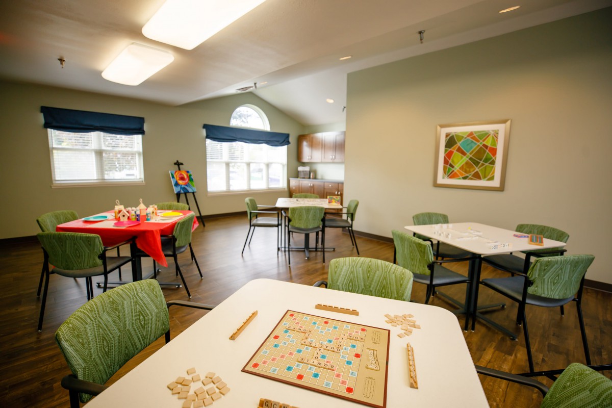 A community recreation room featuring tables with board games and chairs, offering a welcoming space for social activities.