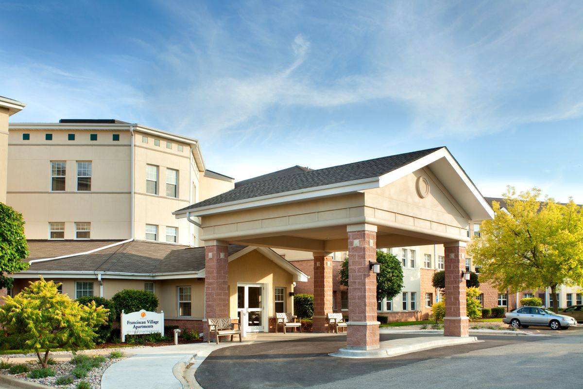 A modern building entrance with a covered driveway and clear skies above.