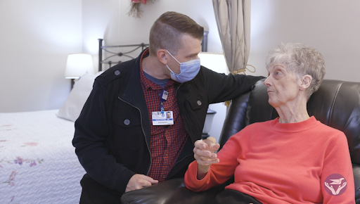 A healthcare worker attentively engages with an elderly patient, providing support and companionship.