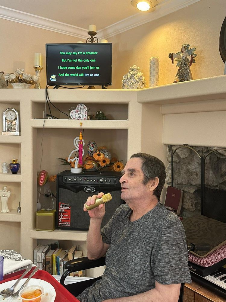 A person singing karaoke indoors, holding a microphone with song lyrics displayed on the television screen.