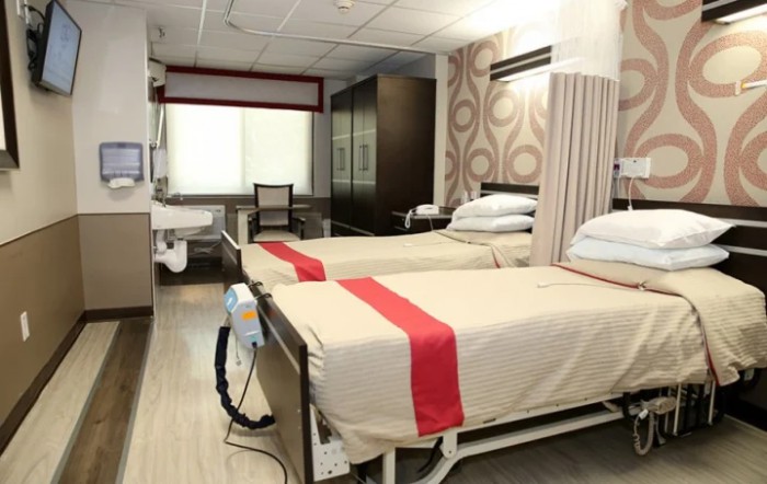 A modern hospital room with two beds and medical equipment.