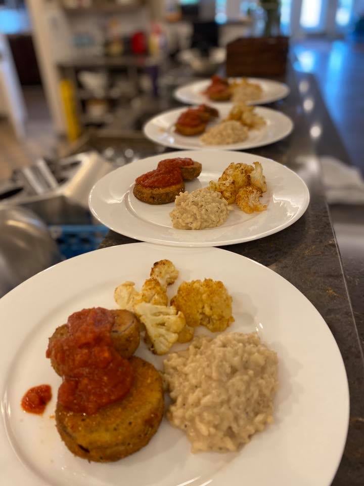 A series of plates with seasoned rice, roasted vegetables, and sauce-topped patties arranged in a row.