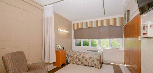 A cozy and well-lit bedroom featuring soft curtains and a floral bedspread.