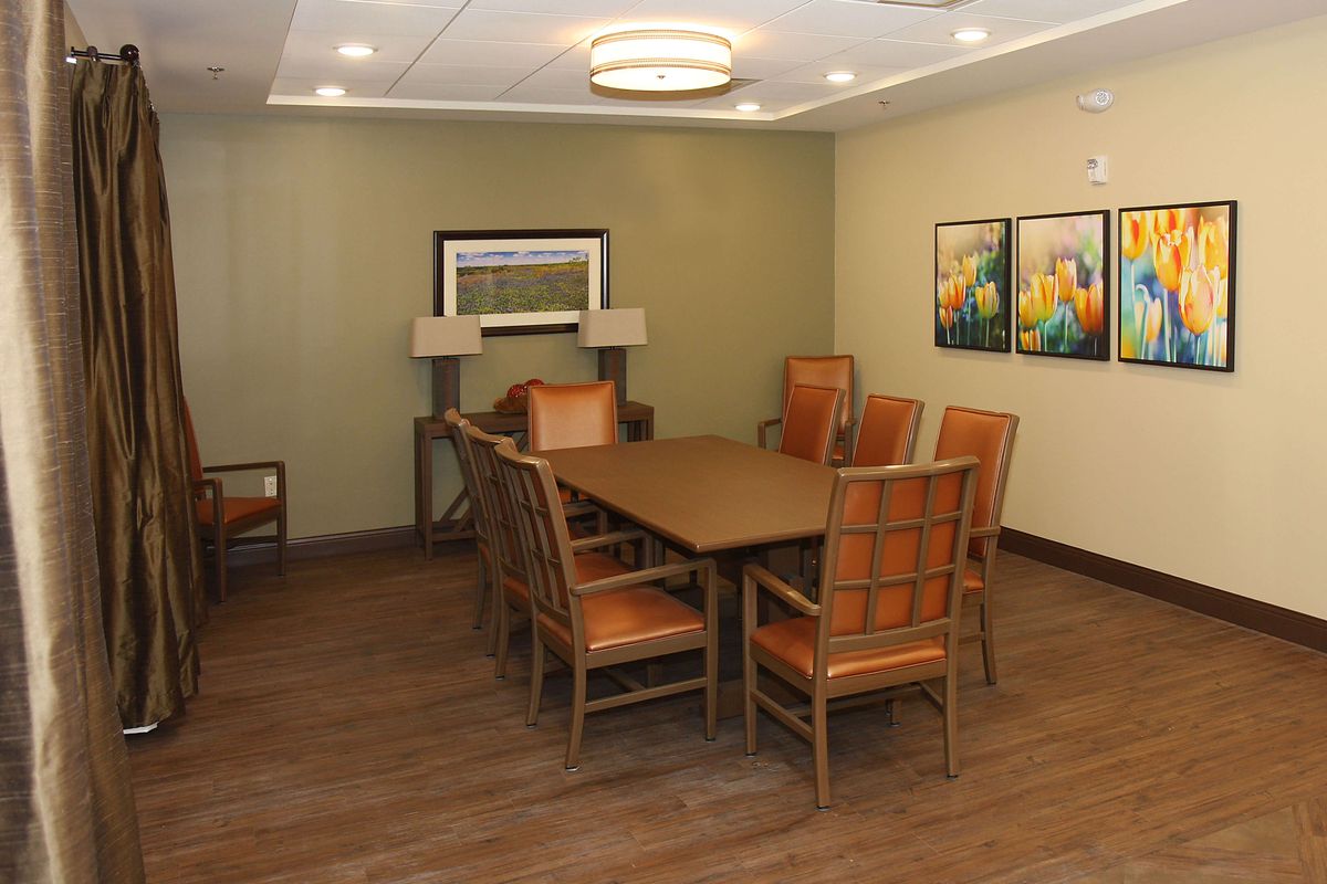 A modern conference room with a large wooden meeting table surrounded by chairs, featuring contemporary artwork and lighting.